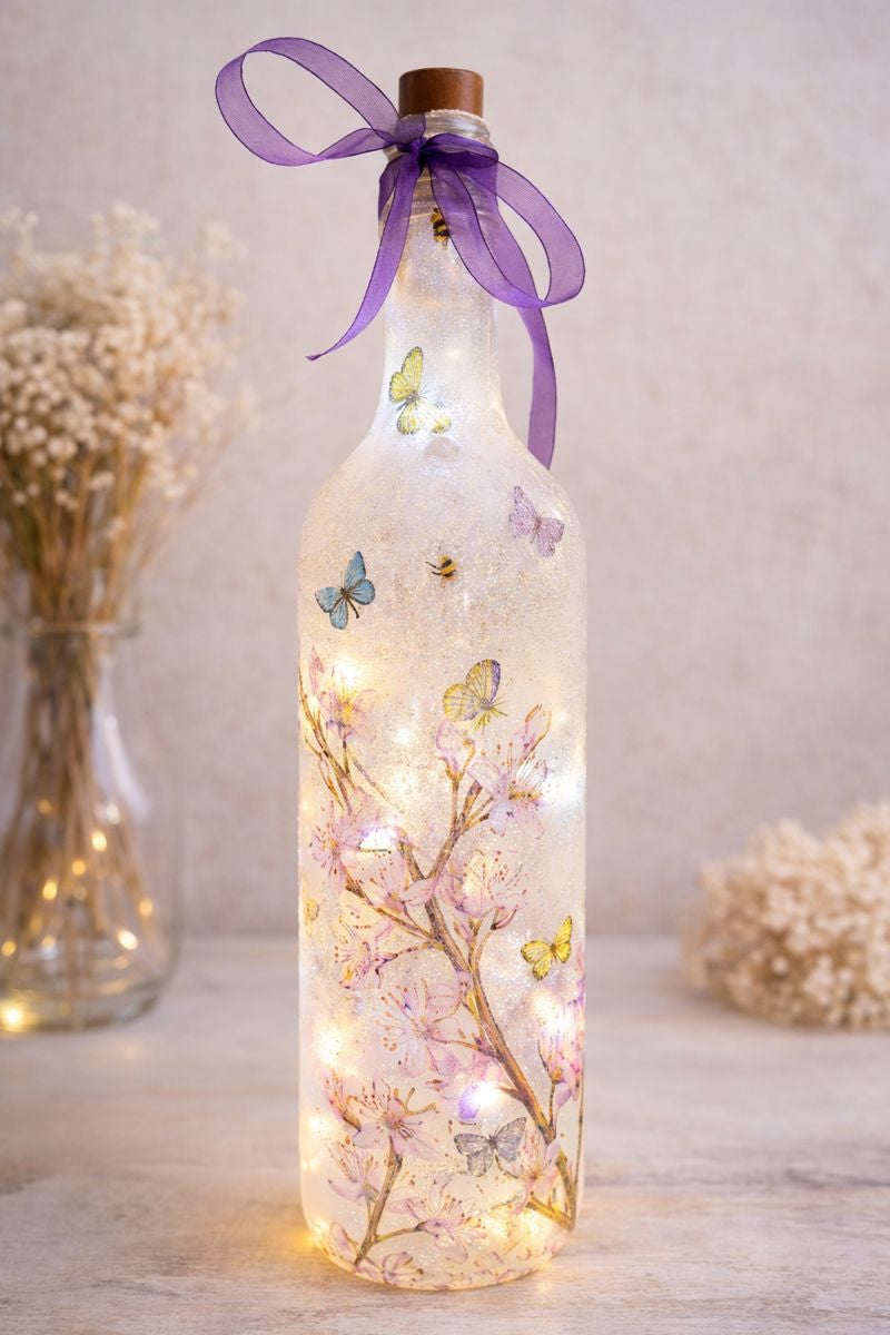 Decorative bottle with LED lights, butterflies, and a purple ribbon on a light background.
