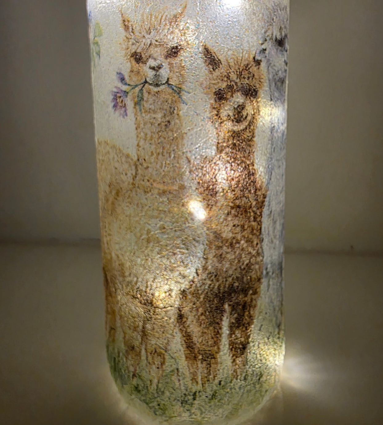 Decorative glass vase with alpaca design on a plain background