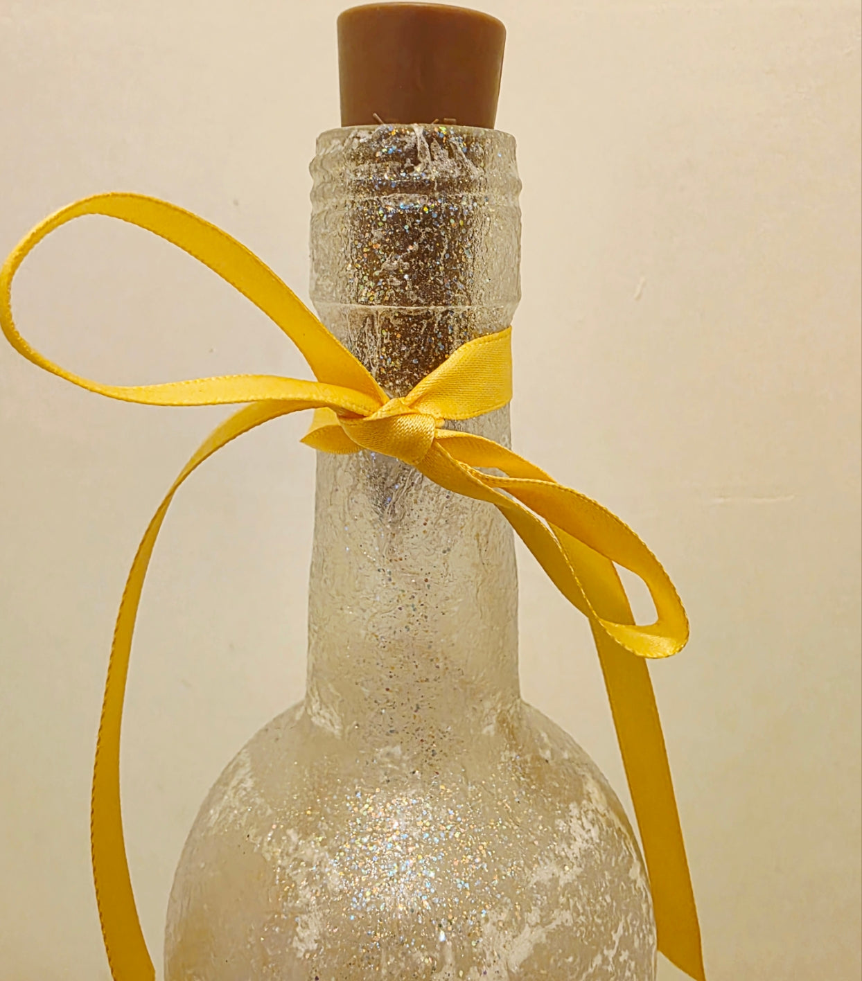 Decorative bottle with a yellow ribbon on a beige background