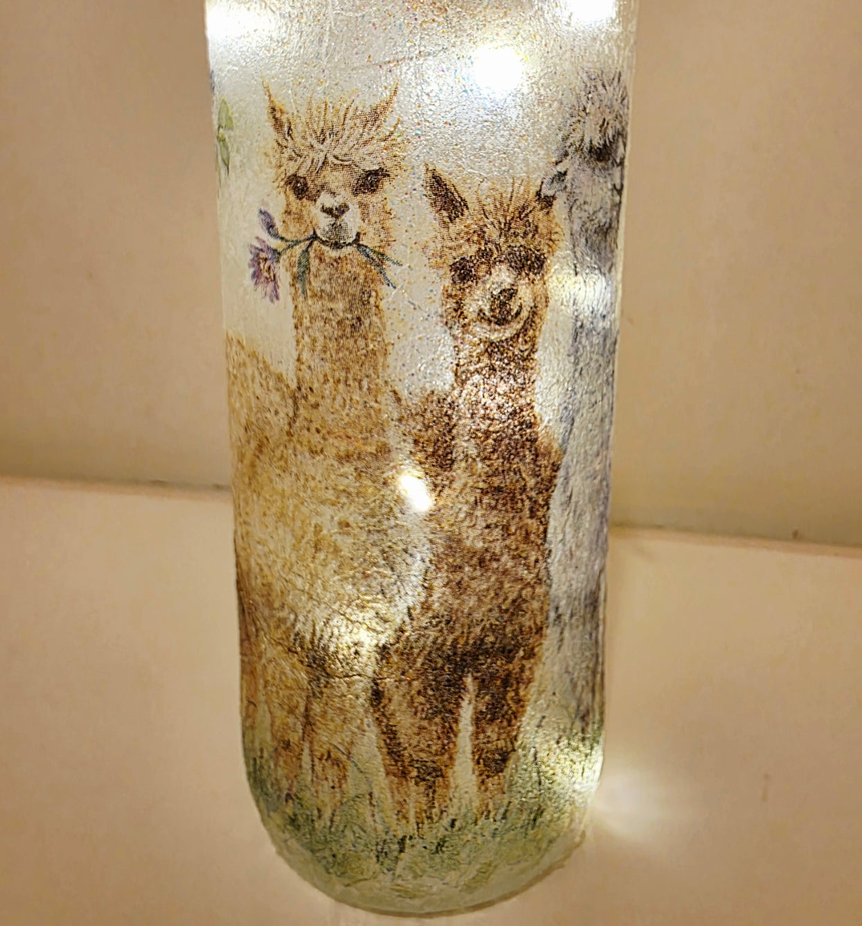 Decorative glass bottle with alpaca design on a beige background