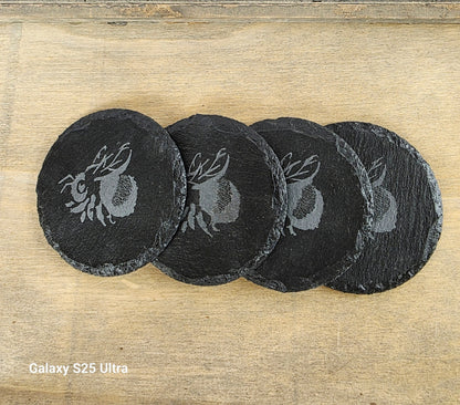 Set of four black slate coasters with Bee design on a wooden surface