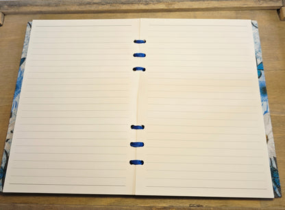 Open notebook with lined pages on a wooden surface. bound with blue ribbon
