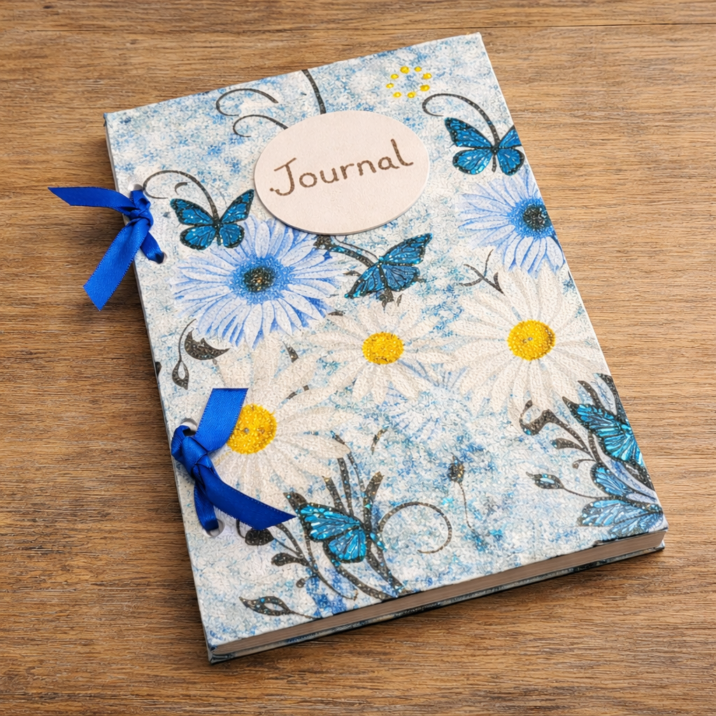Journal with floral design and blue ribbons on a wooden surface