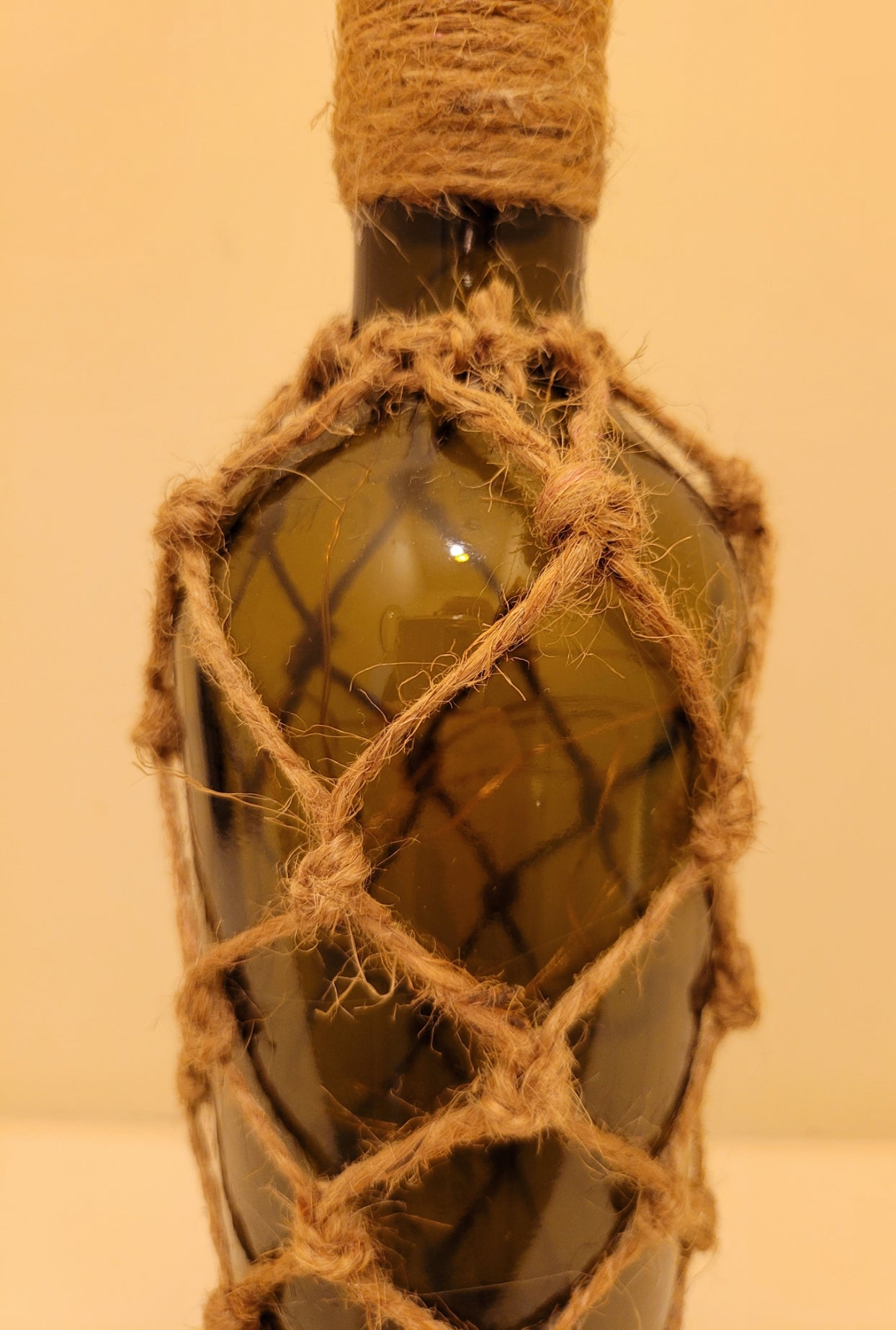 braided jute string bottle with green glass and LED lights. Brown plastic cork