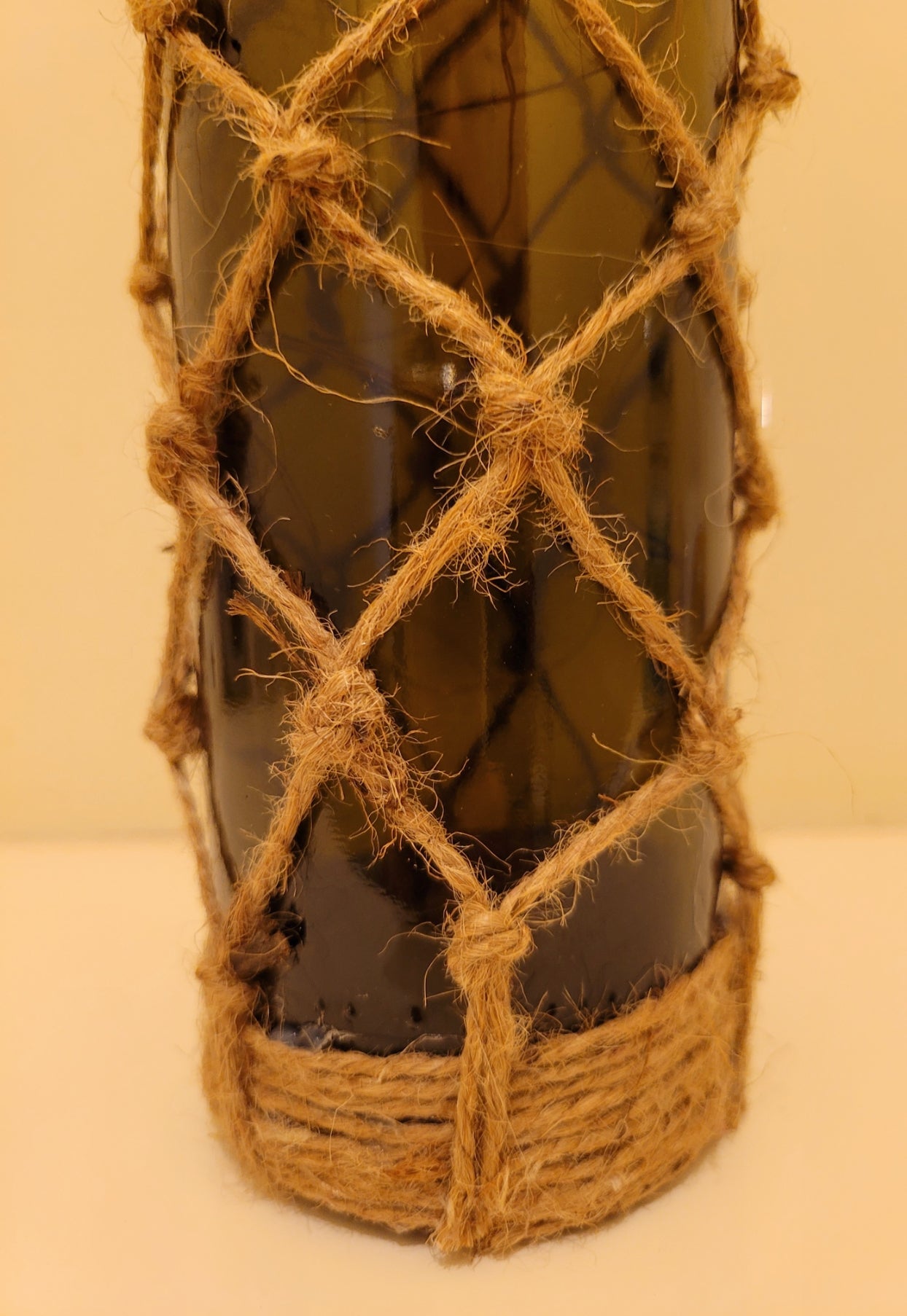 Braided Green Glass Bottle Lamp - Green glass standard wine bottle with jute twine braiding in a diamond pattern. Jute twine around the bottom  of the bottle. Cork LED lights
