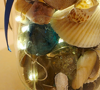 Decorative jar with seashells, glass beads, and LED lights on a beige background