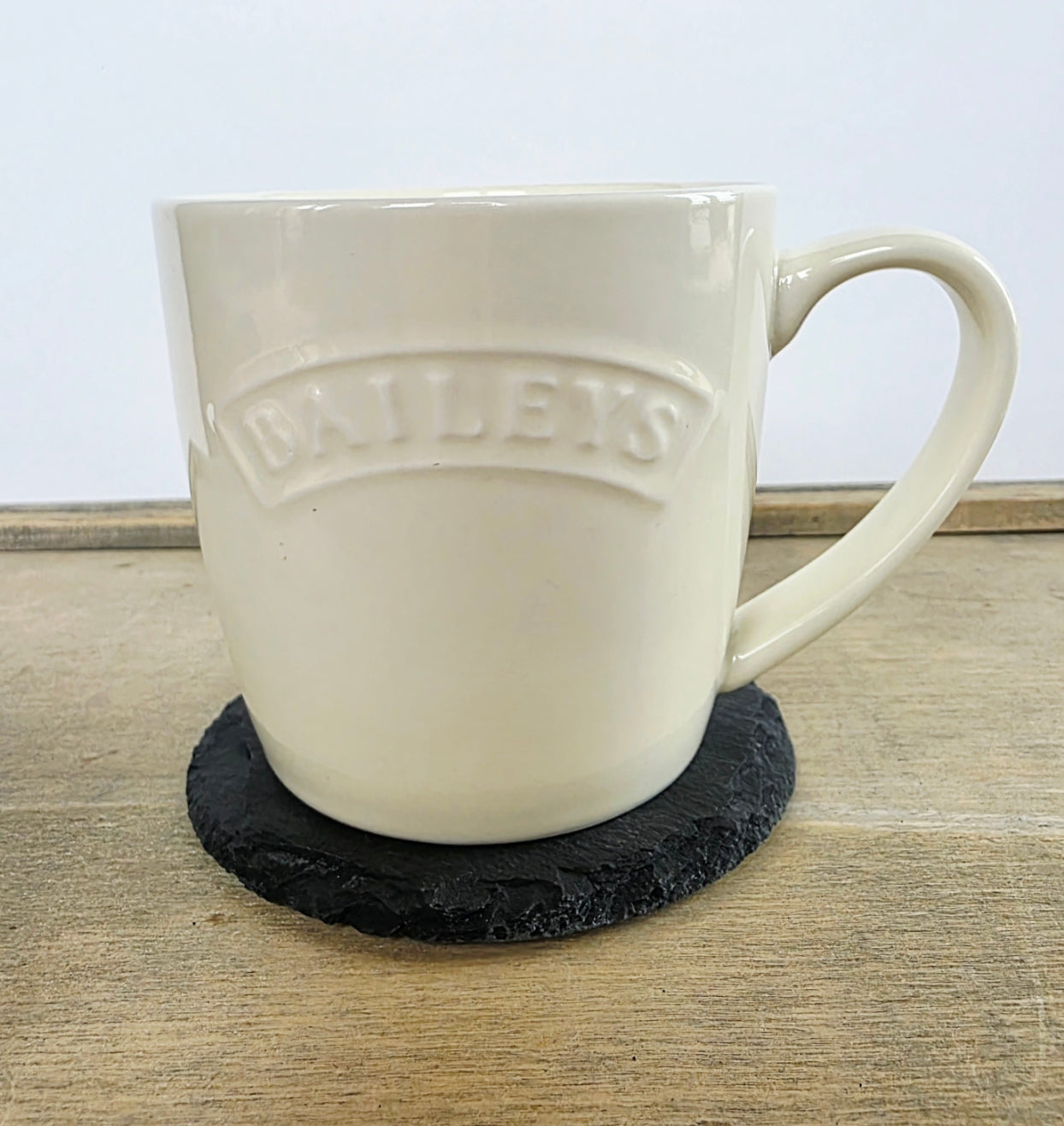 White Baileys mug on a black coaster with a light background