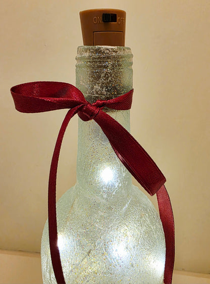 Red ribbon tied around the neck of a wine bottle. Brown cork with black switch