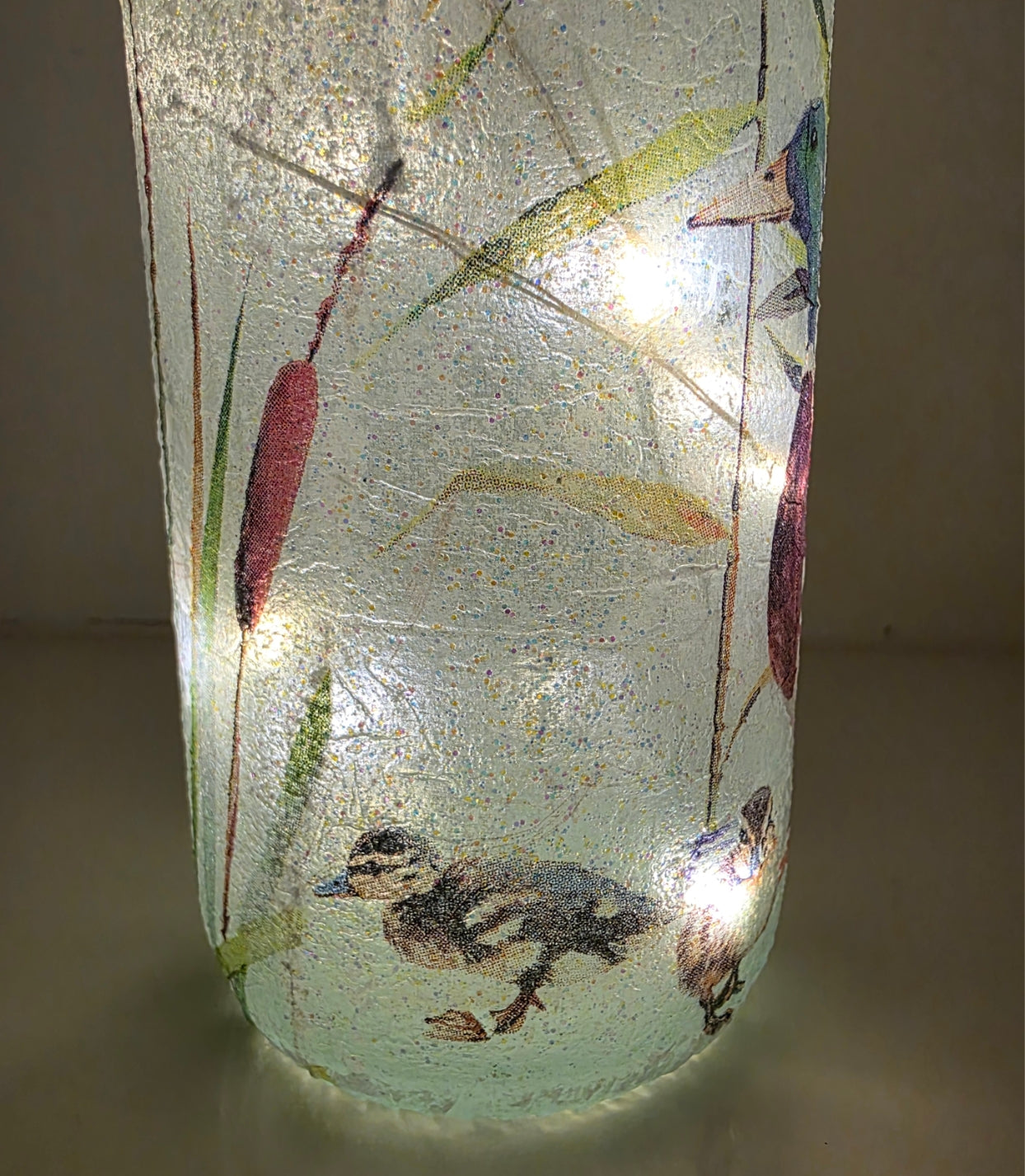 duckling decoupaged onto the bottom of a lit up wine bottle