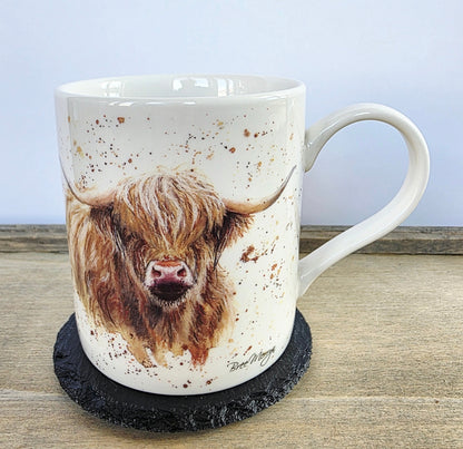 Mug with a highland cow design on a black round slate coaster. wooden surface