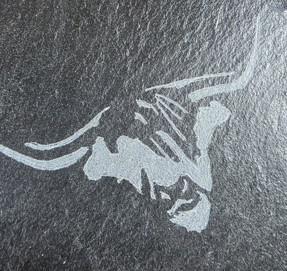 Engraved cows head design on a dark stone surface