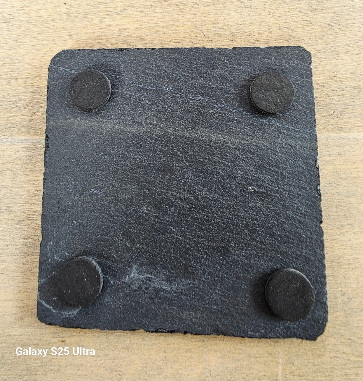 square slate coaster showing four protective pads on the underside