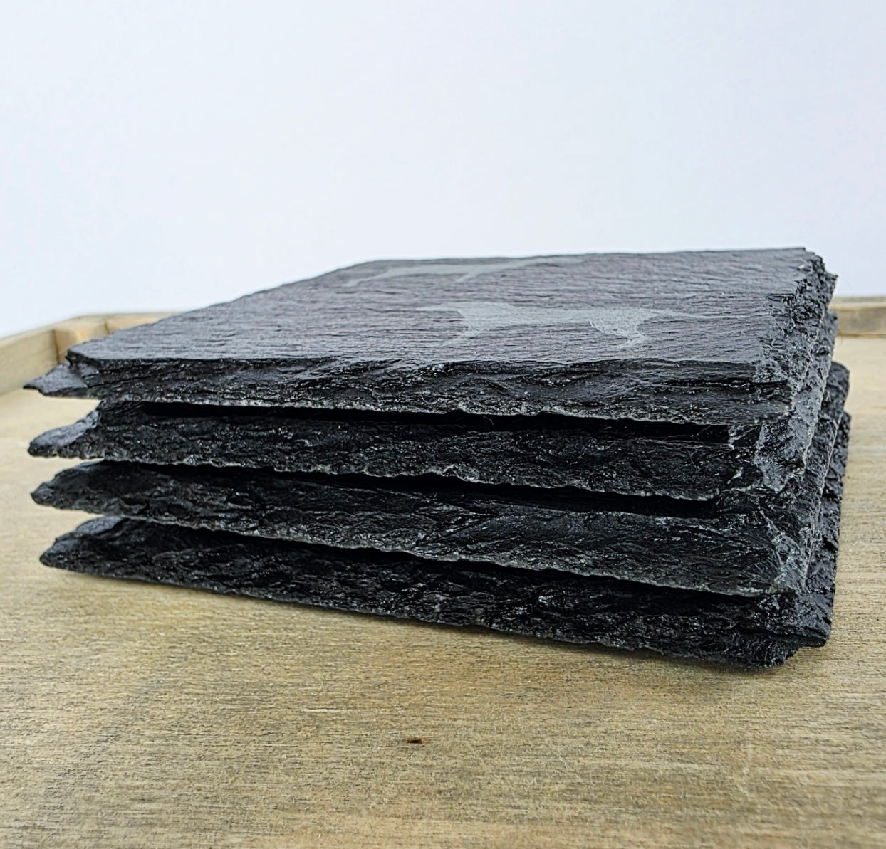 four slate coasters stacked on top of one another