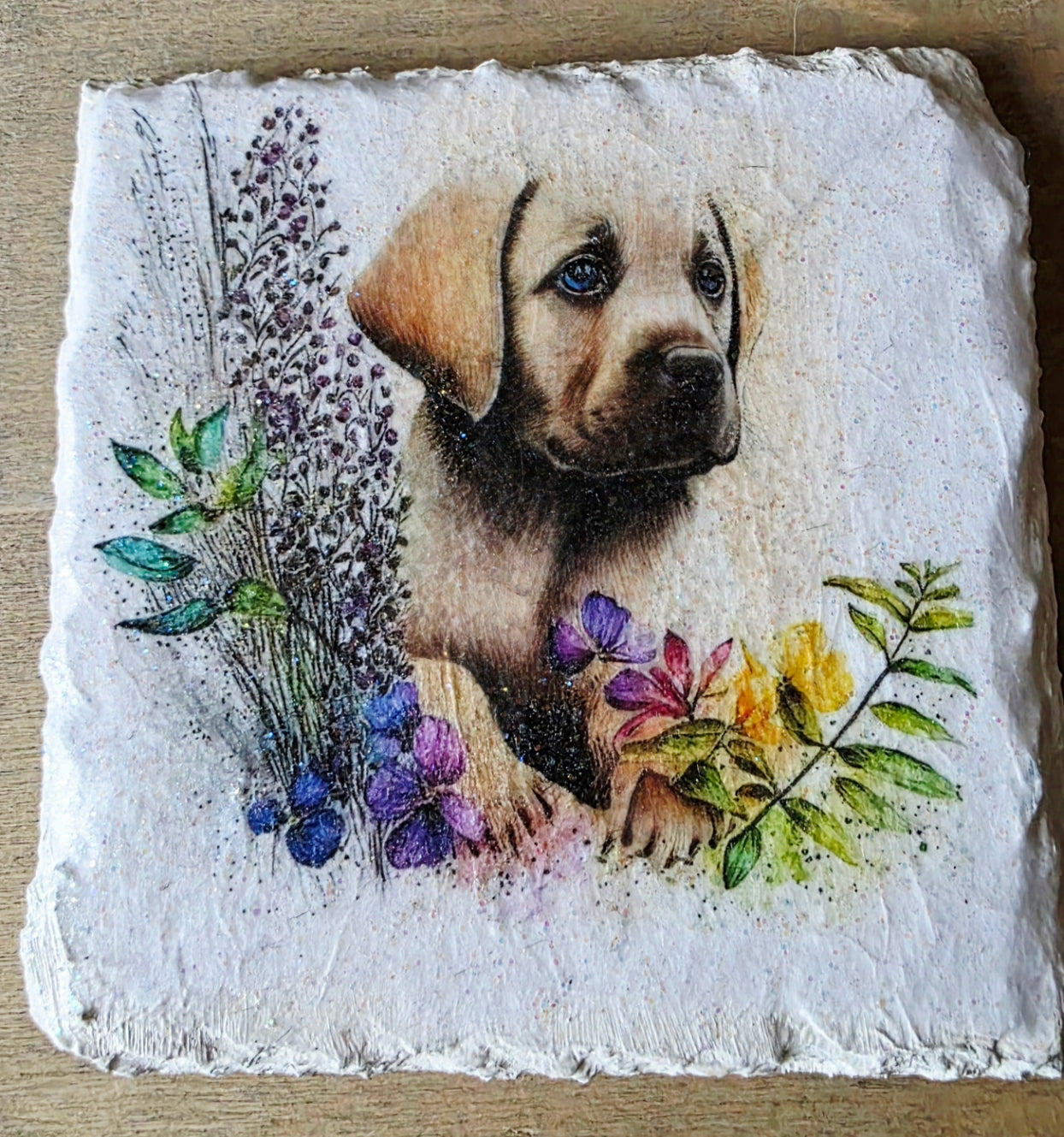 Artistic depiction of a golden labrador puppy surrounded by flowers on a white painted slate coaster