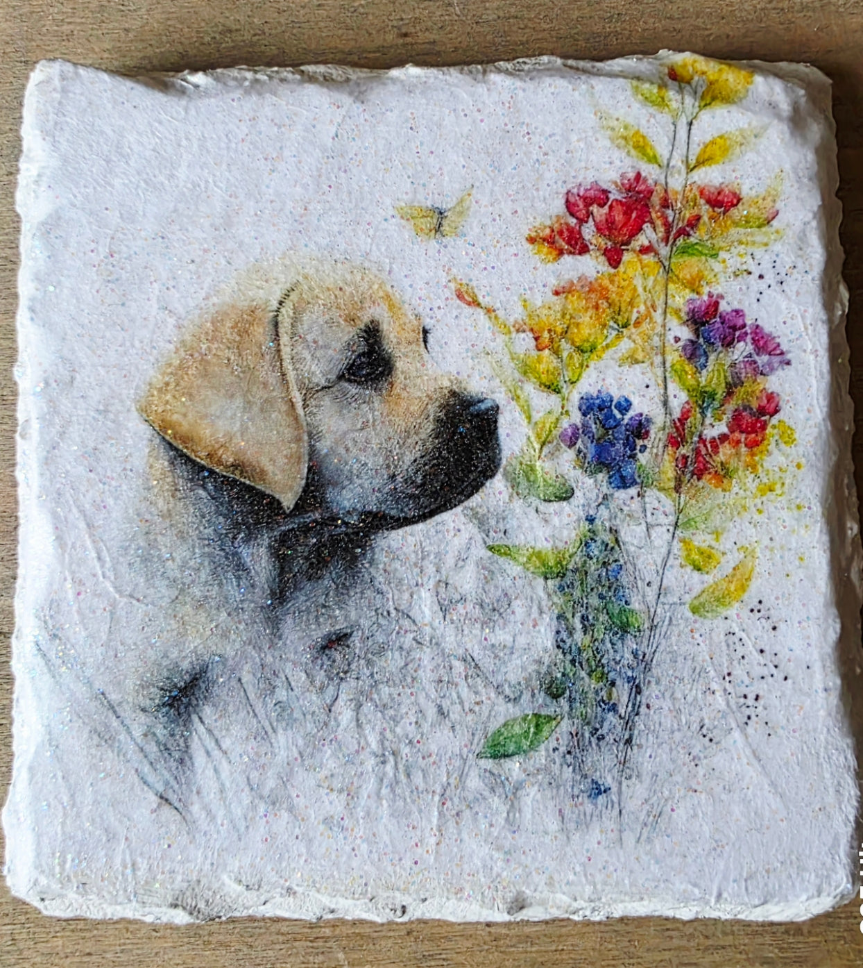 Artistic depiction of a golden labrador puppy surrounded by flowers on a white painted slate coaster