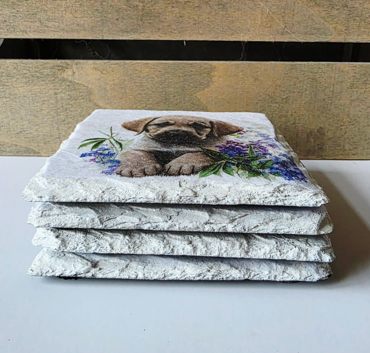 Stack of stone coasters with a golden labrador puppy and floral design on a white surface.