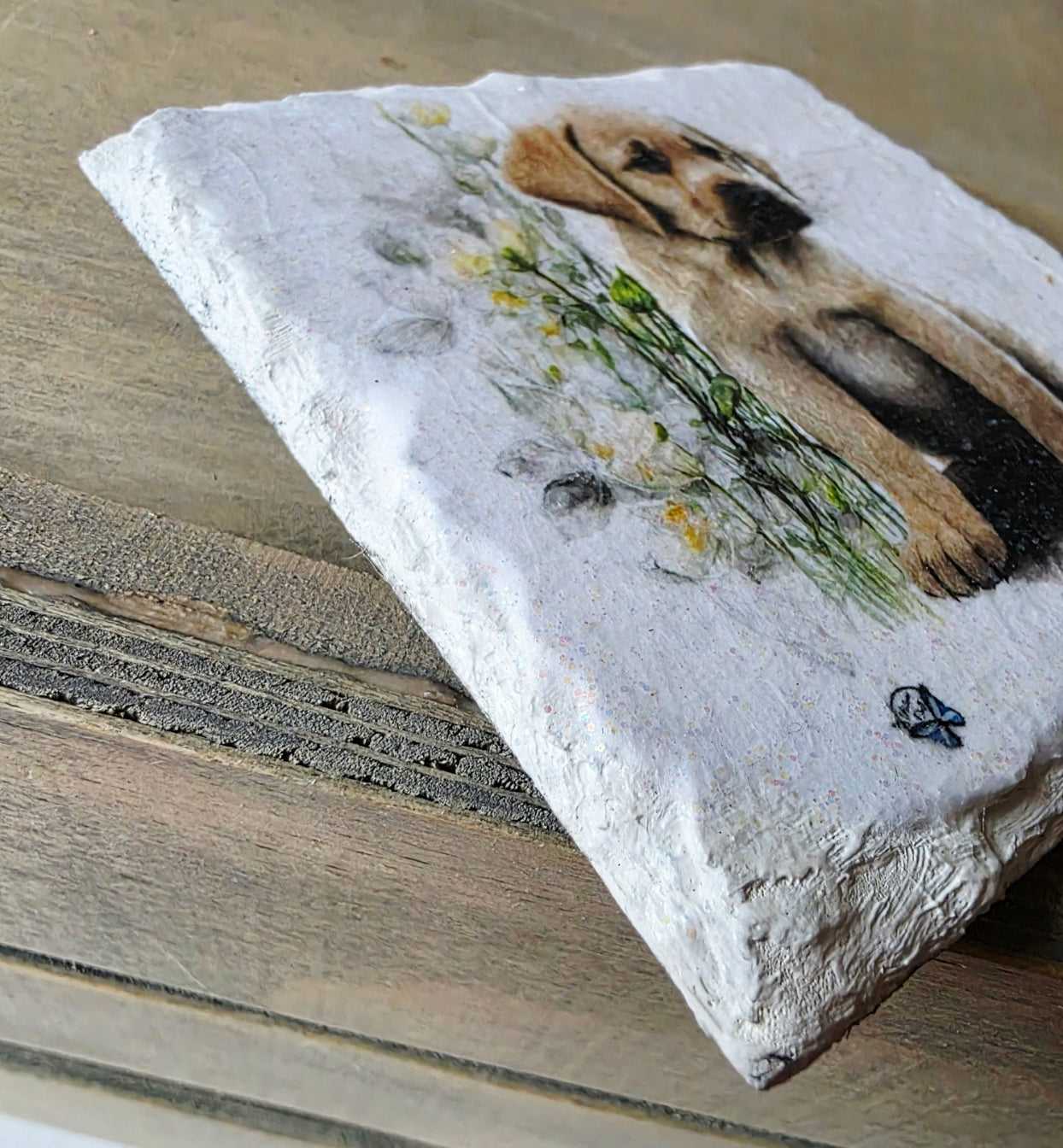 Decorative slate white painted coaster with a labrador puppy design and flowers on a wooden surface