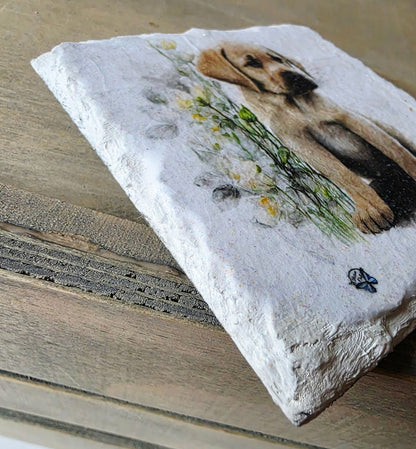 Decorative slate white painted coaster with a labrador puppy design and flowers on a wooden surface