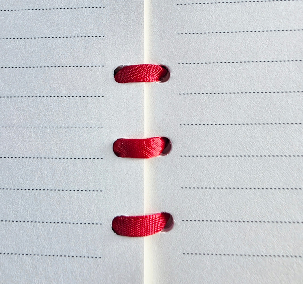 Red ribbon binding on white lined paper. 