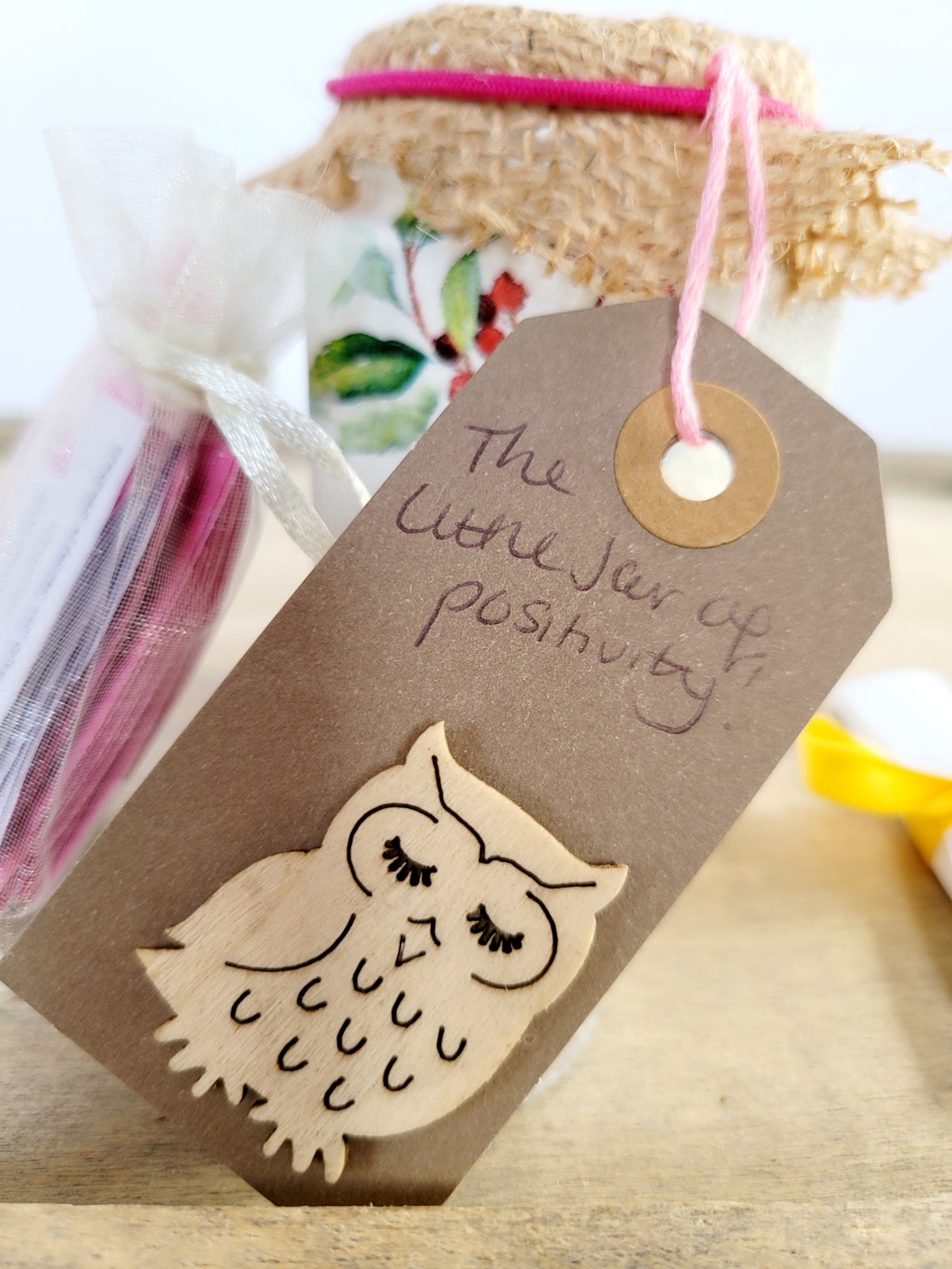 brown tag stating' the little jar of positivity and a beige owl decoration