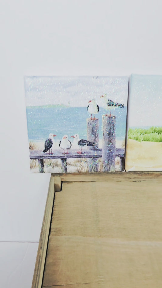 A video of three beach scene canvases - a beach hut, seagulls and a lighthouse. All images a re square
