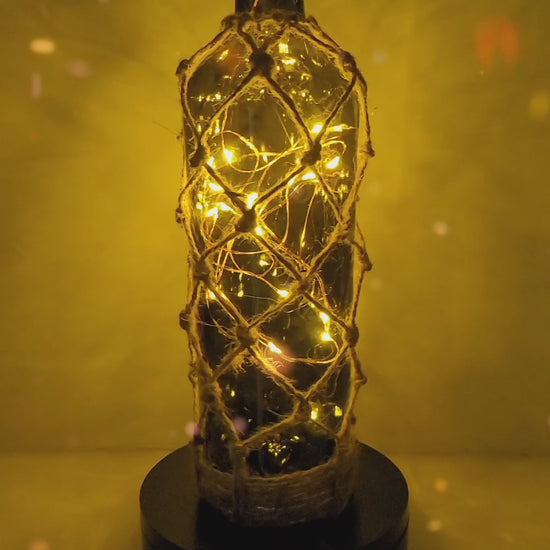 Rotating example of a green glass bottle with jute twine braided all the way down, with LED lights switched on inside