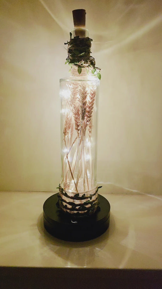 A wheat filled bottle with jute twine and leaves, LED lights, rotating on a stand