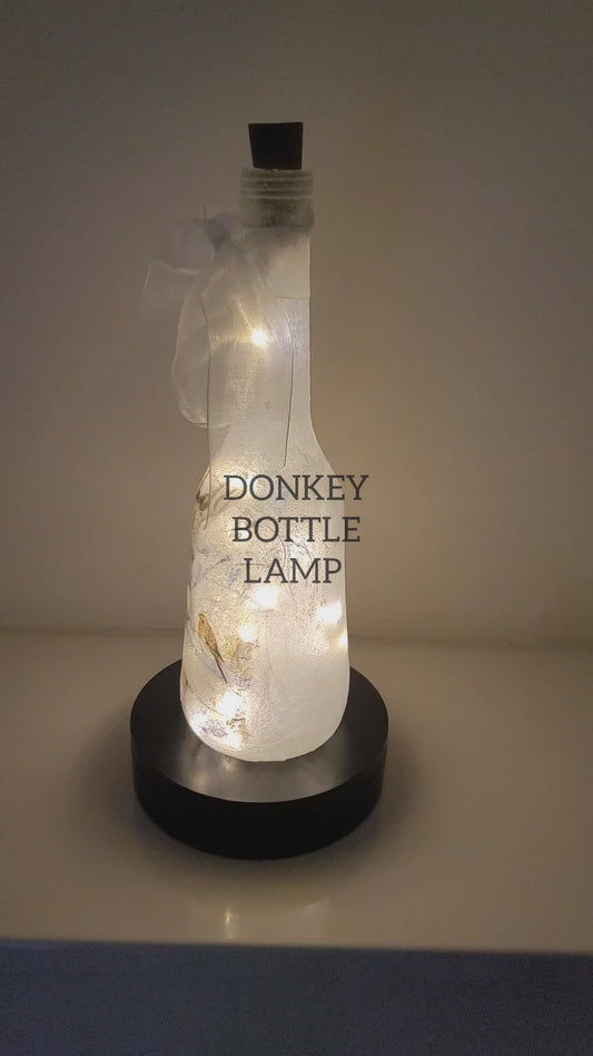 A video of a donkey themed bottle lamp rotating on a stand, lit up