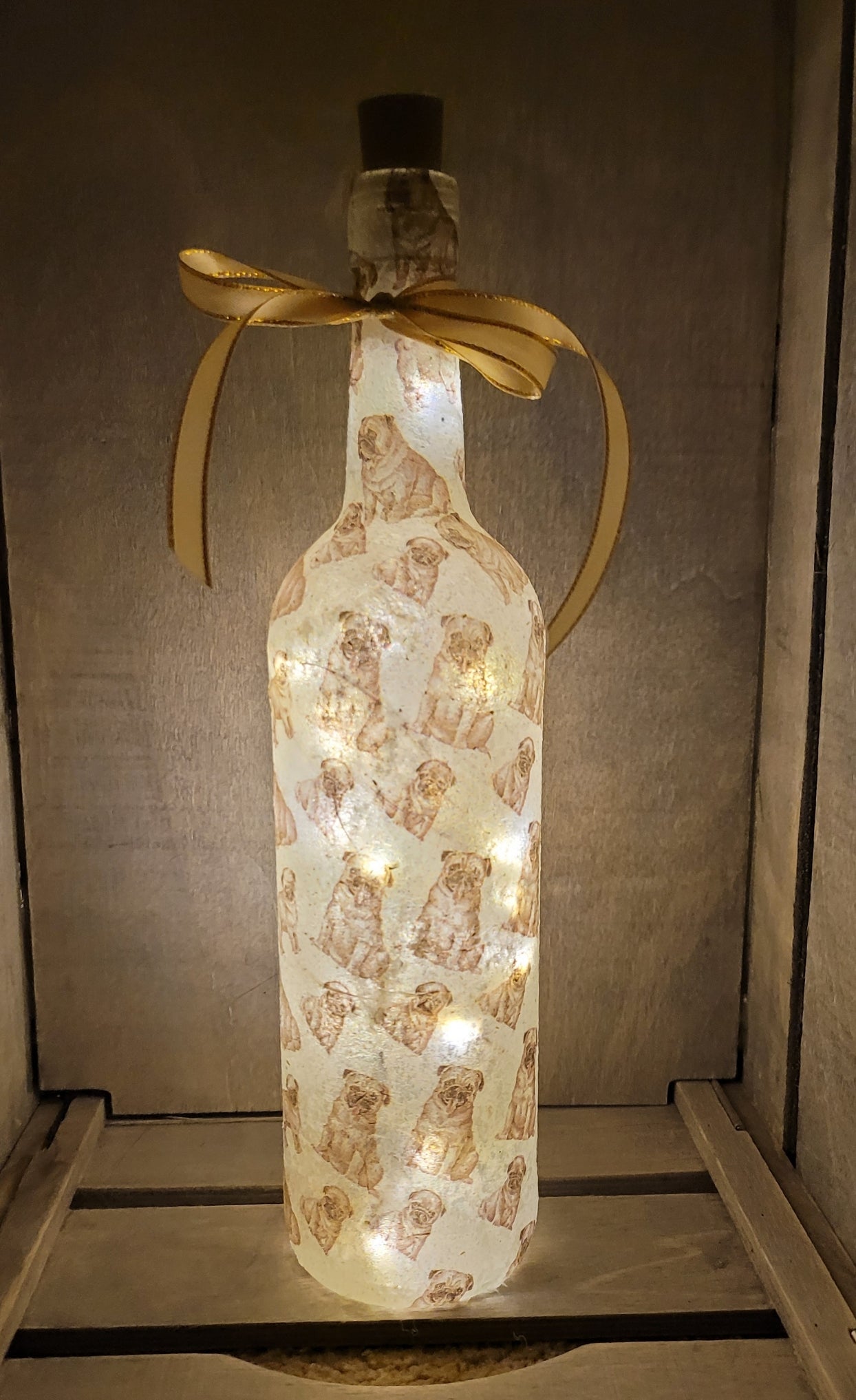 wine bottle decorated with tiny pug dog images. Cork LED lights and gold ribbon embellishment