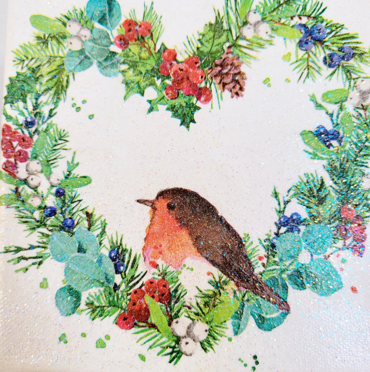Decoupage artwork on canvas. Square design with a robin surrounded by holly, berries, and greenery on a white background.