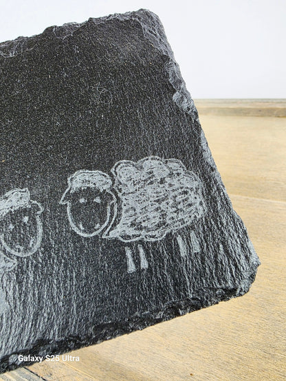 Black stone with engraved sheep design on a wooden surface