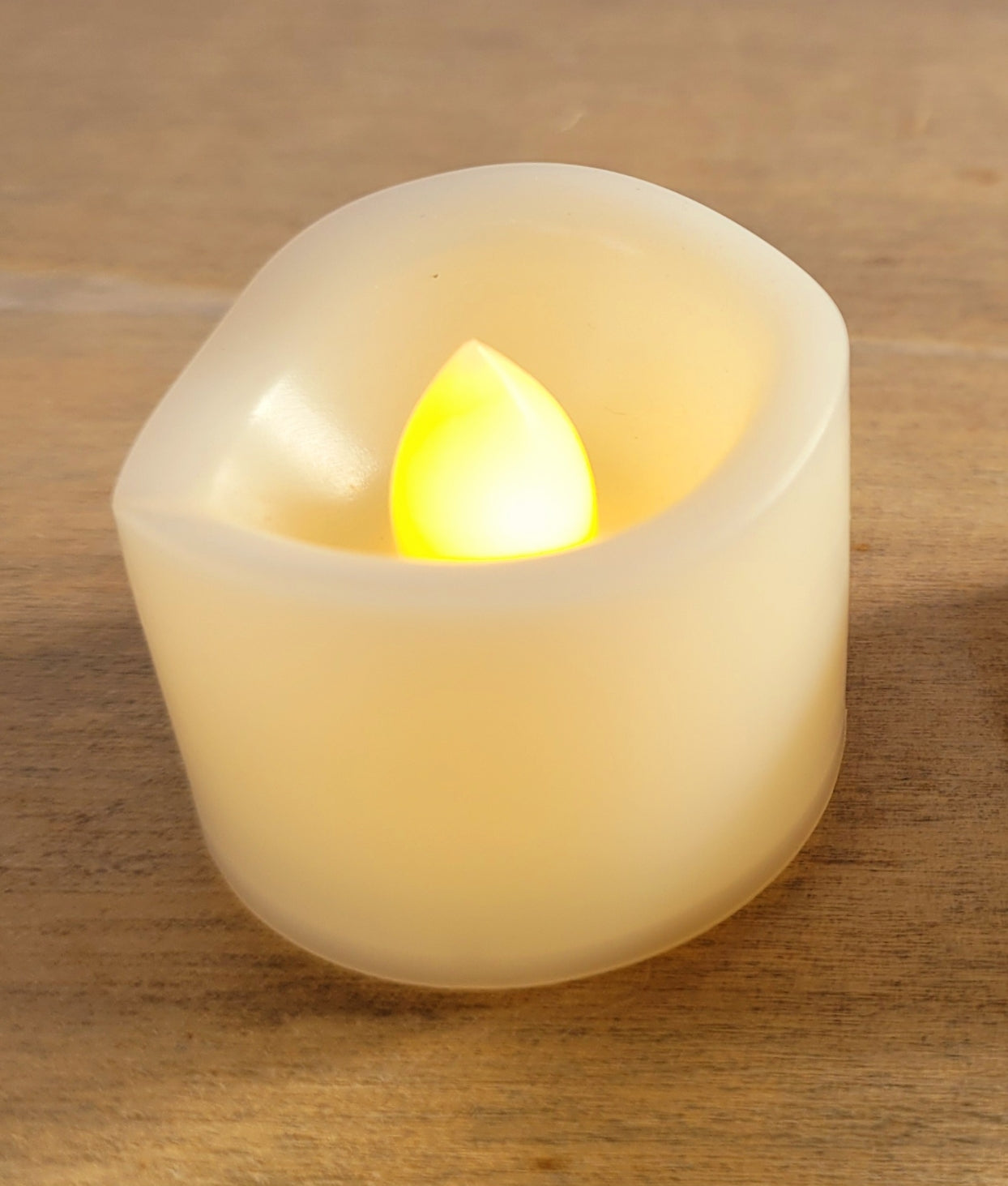 cream coloured plastic votive flameless candle, lit up