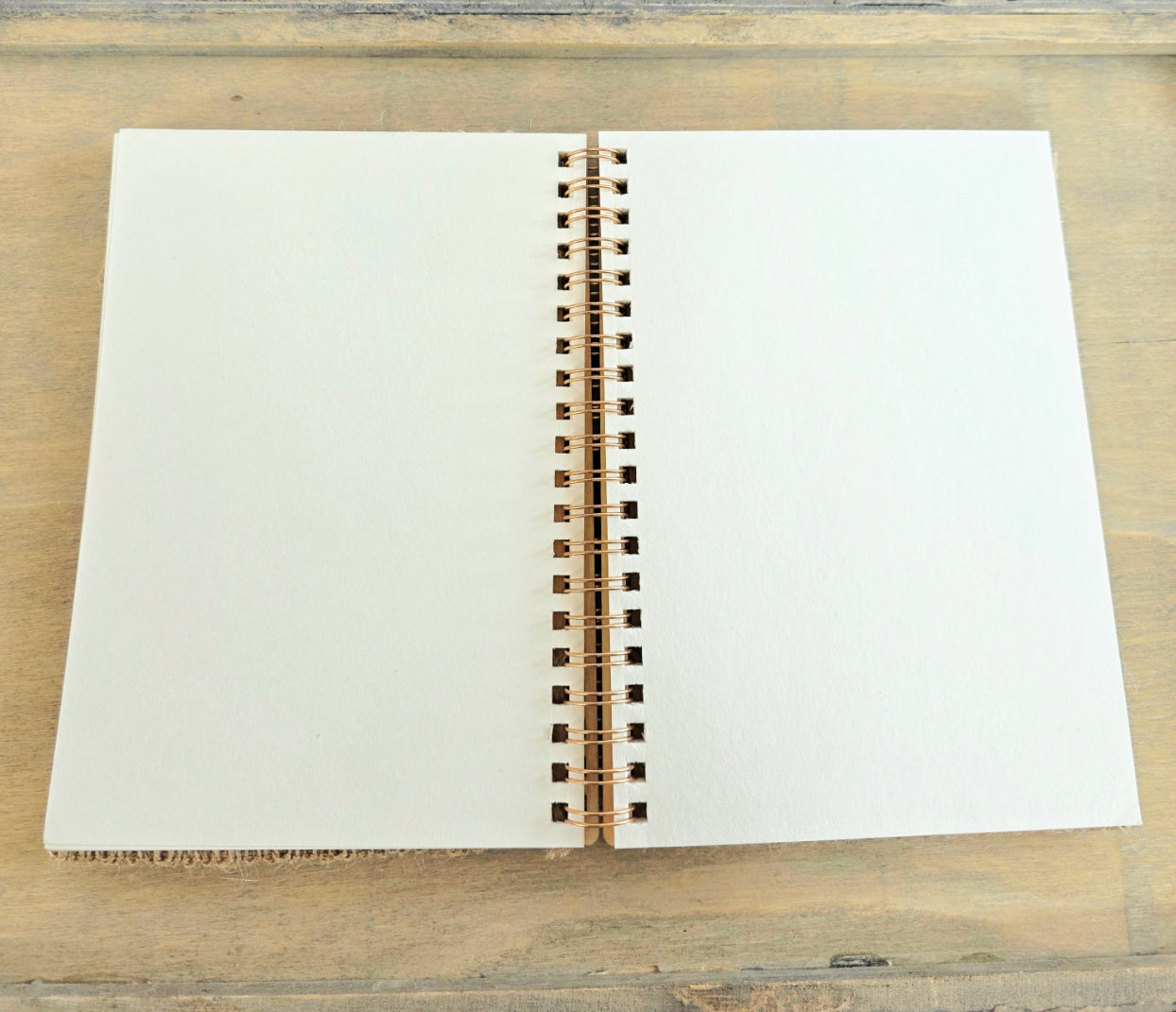 Open spiral bound notebook with blank pages on a wooden surface