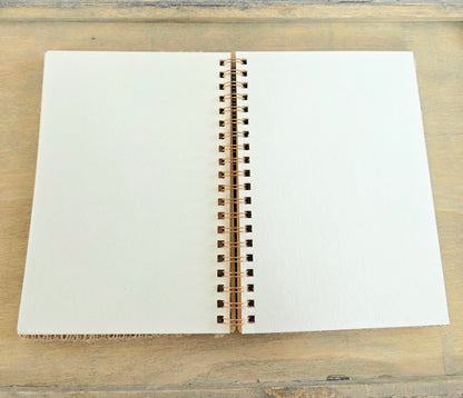 Open spiral bound notebook with blank pages on a wooden surface