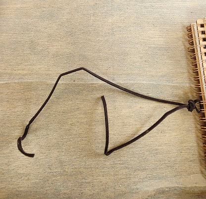 dark brown faux suede tie on the edge of a spiral bound journal