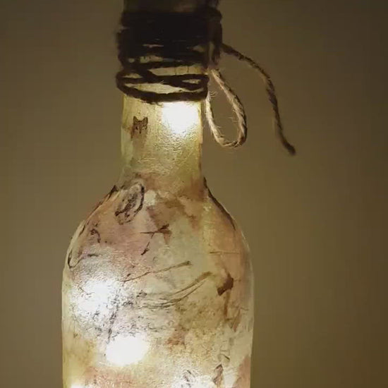 Rotating example of a lit up wine bottle with fox detailing and cork LED lights. Jute string bow