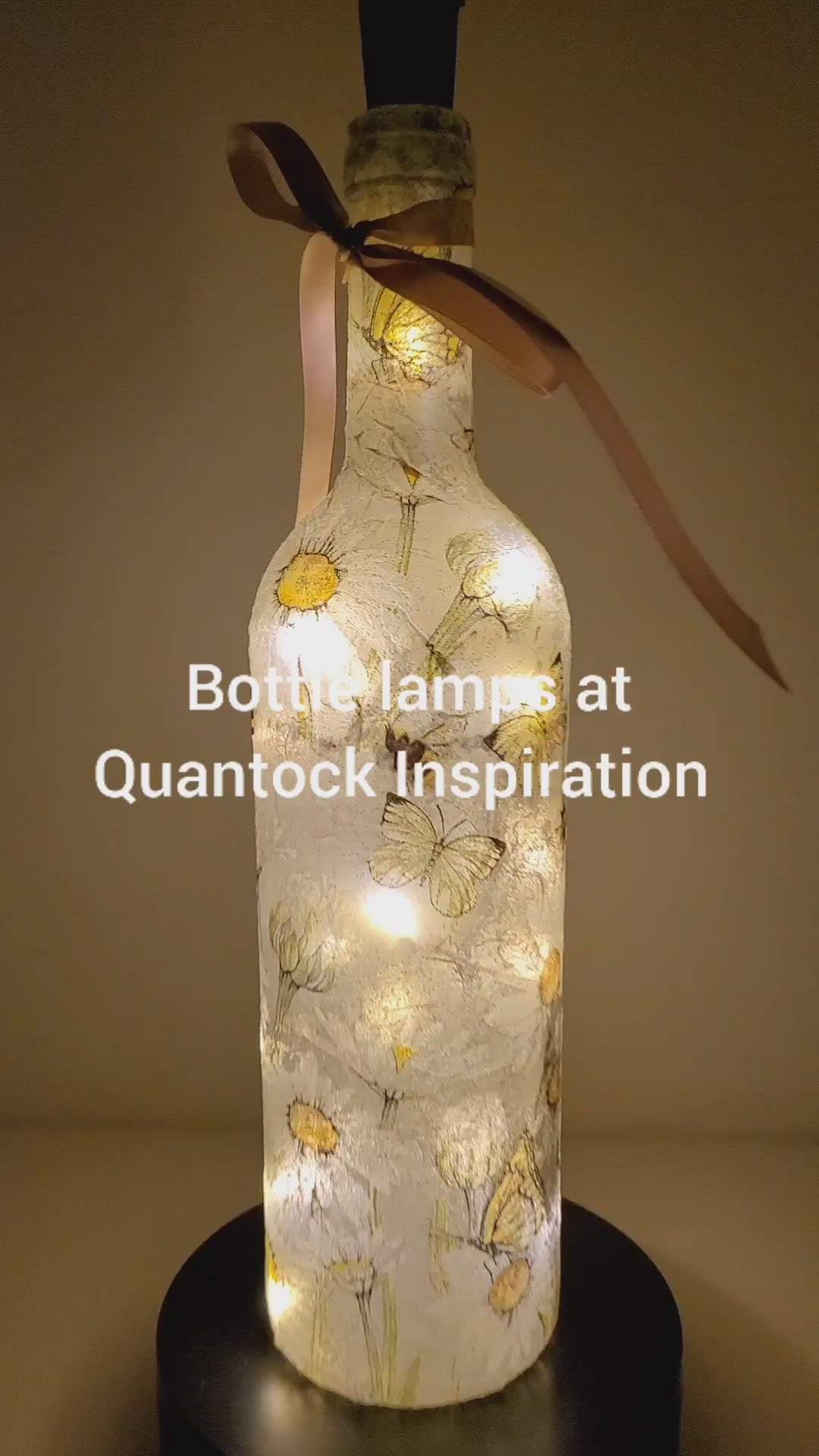 Rotating example of a Lit up bottle with Bumble bees and daisies detail. Cork LED lights, Rose gold coloured bow